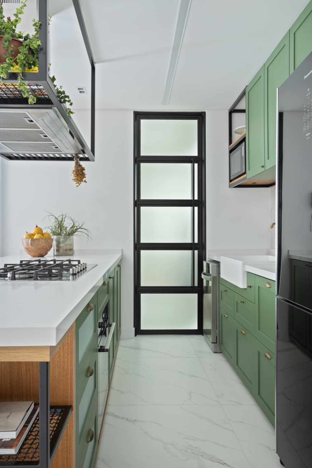Cozinha verde com bancada branca e torneira dourada