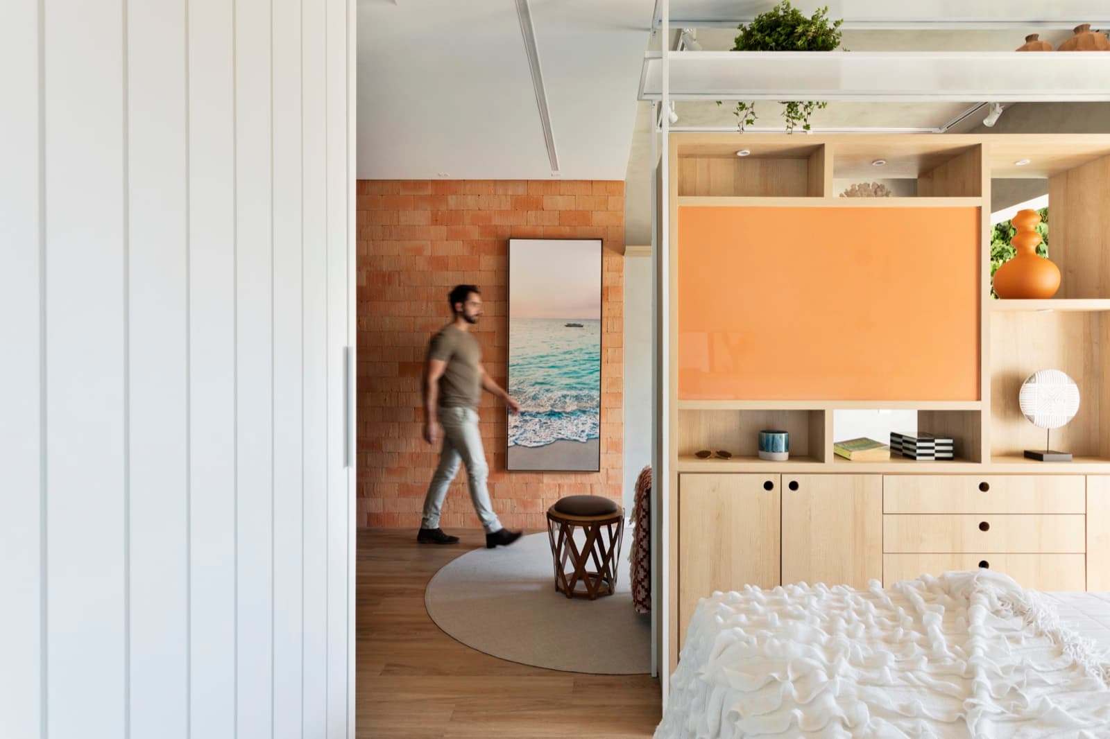 Sala com estante em laca laranja e parede de tijolo