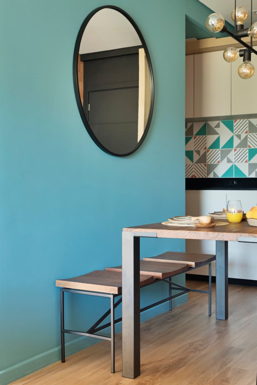 Sala de jantar com parede azul e espelho redondo
