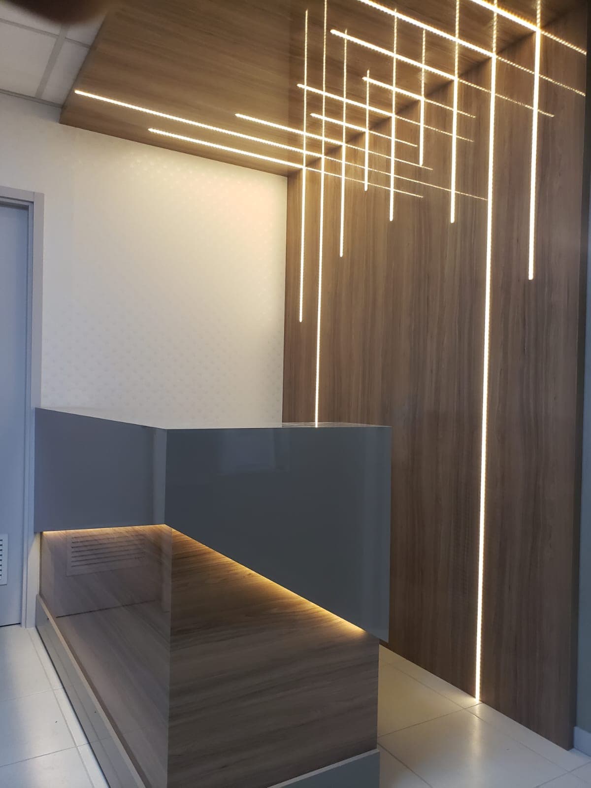 Recepção com painel amadeirado e iluminação linear