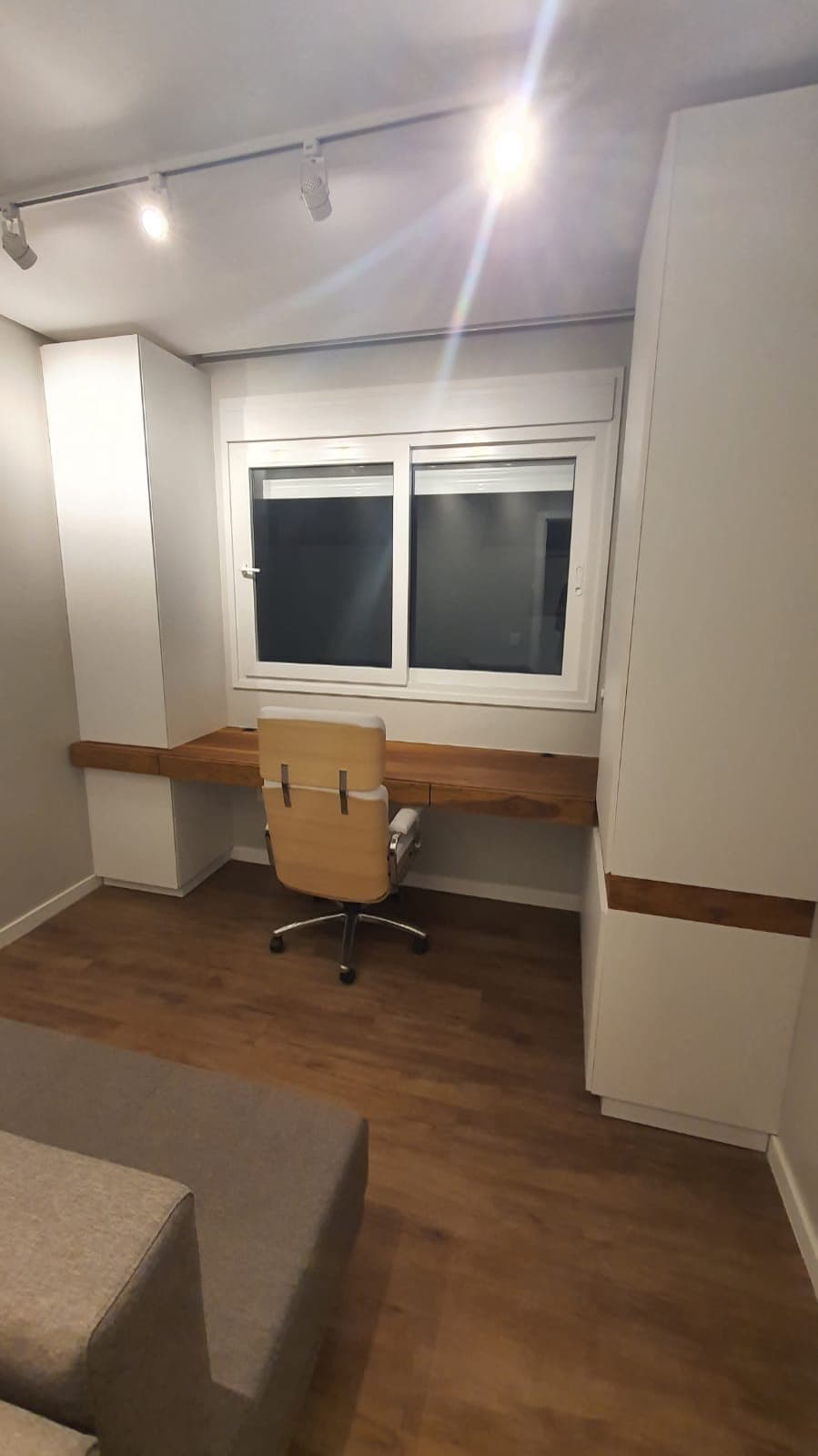 Home office com bancada de madeira e armários brancos