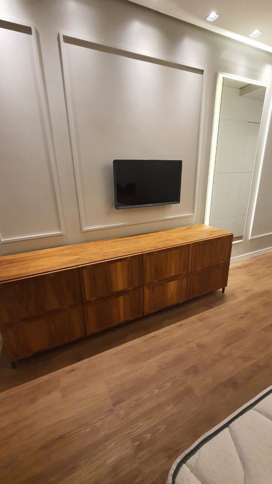 Cômoda de madeira e painel de boiserie no dormitório